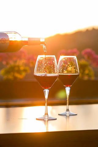 Pouring Wine into Two Glasses at Sunset